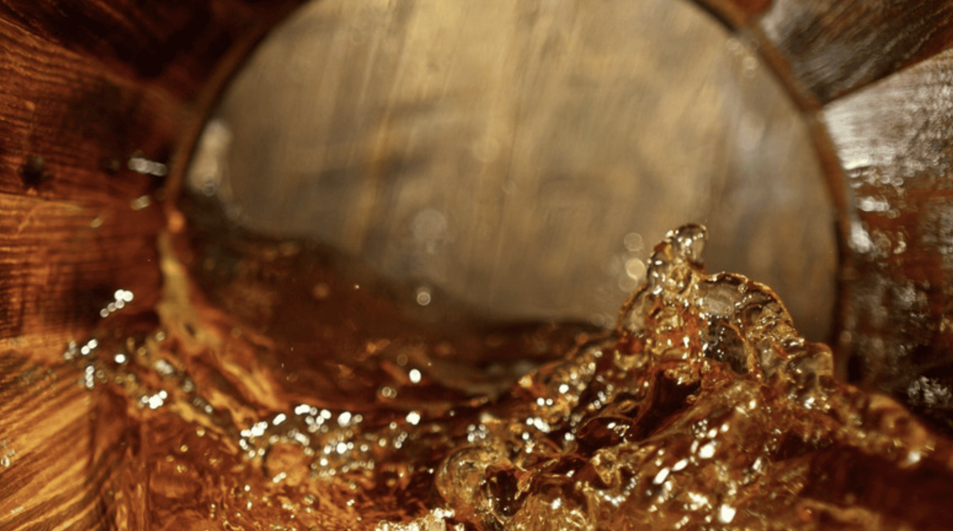 Bourbon whiskey splashing inside a charred oak barrel during the aging process