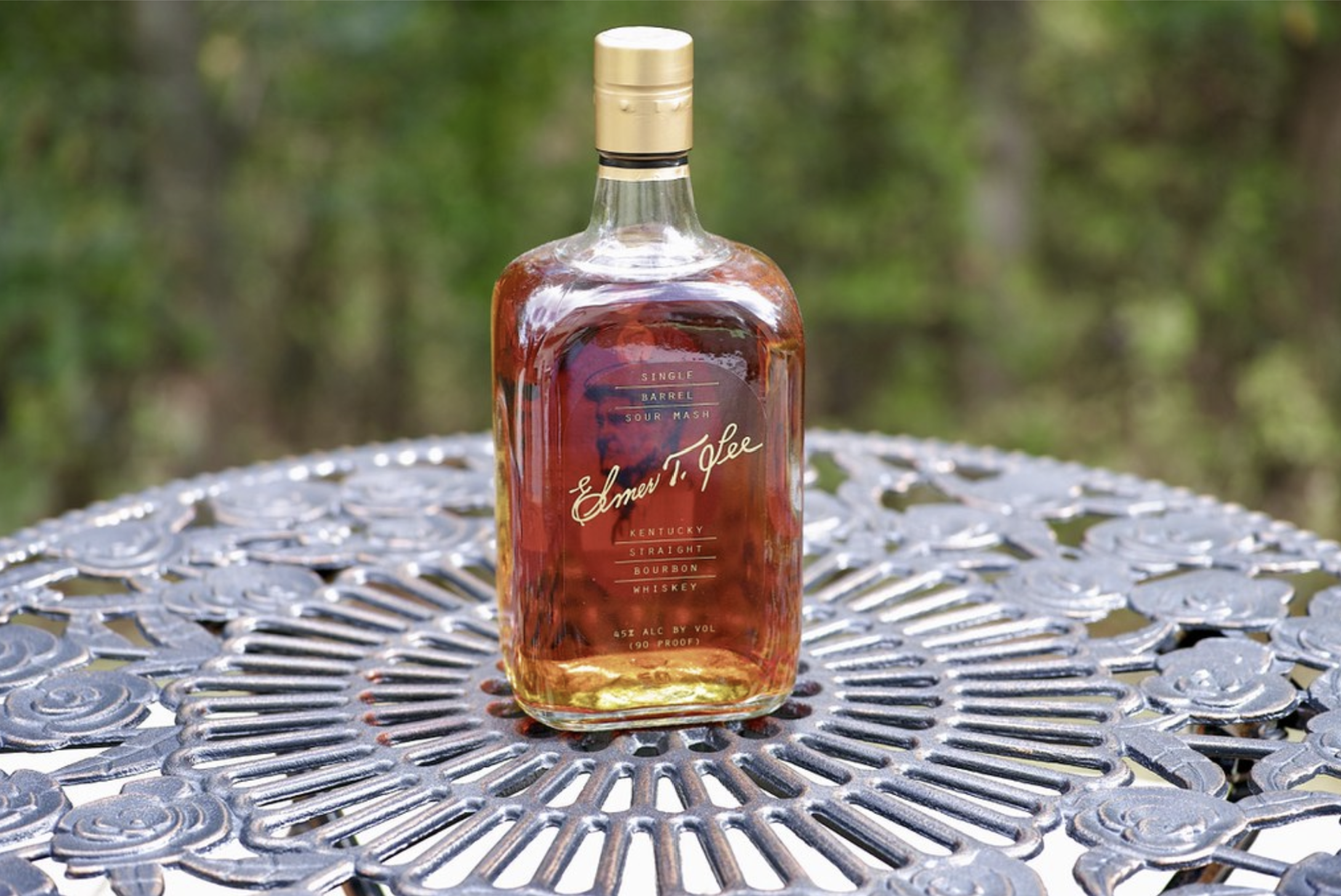 Elmer T. Lee Single Barrel bourbon bottle sitting on a metal garden table outside
