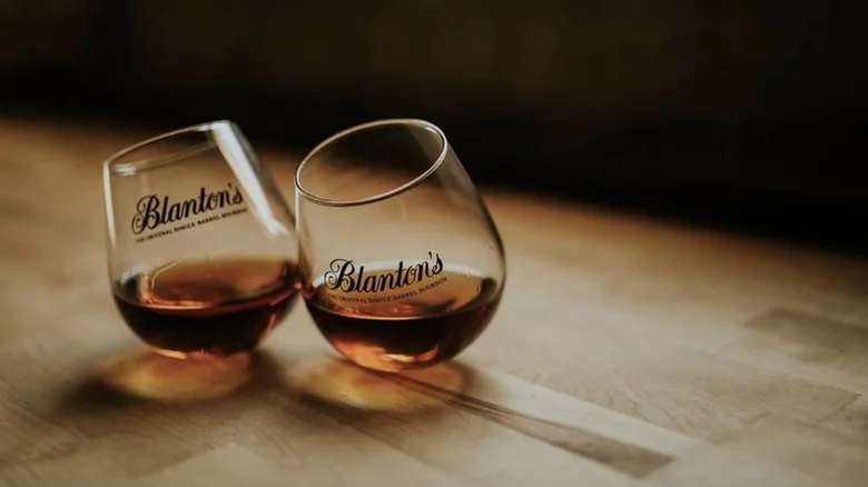 Three people clinking glasses of blantons special reserve over ice at a bar